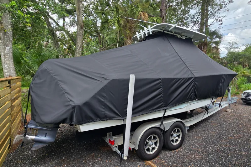 Slide: The Image of 2018 Sea Hunt Gamefish 27 boat covered on trailer in wooded area. - 53