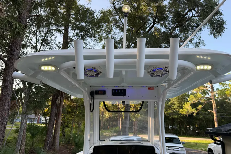 Slide: The Image of 2018 Sea Hunt Gamefish 27 boat with T-top, rod holders, and LED lights in a wooded setting. - 17