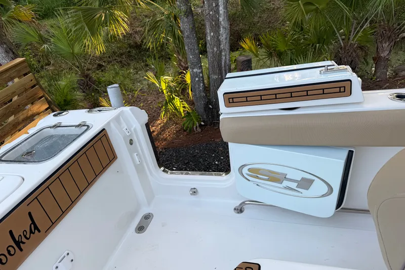 Slide: The Image of 2018 Sea Hunt Gamefish 27 boat interior with storage compartments and lush greenery background. - 50