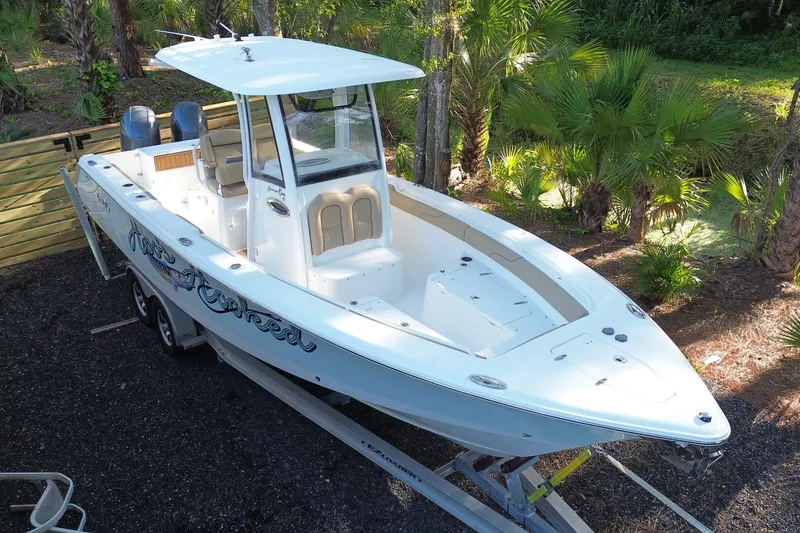 Slide: The Image of 2018 Sea Hunt Gamefish 27 boat on trailer, surrounded by lush greenery. - 1