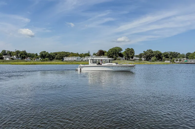 Slide: The Image of 2024 Nimbus Commuter 9 boat cruising on a serene lake under a clear blue sky. - 4