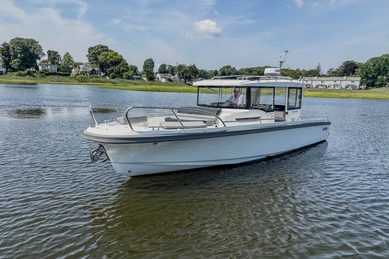 Slide: The Image of 2024 Nimbus Commuter 9 boat cruising on a serene lake under a clear blue sky. - 2