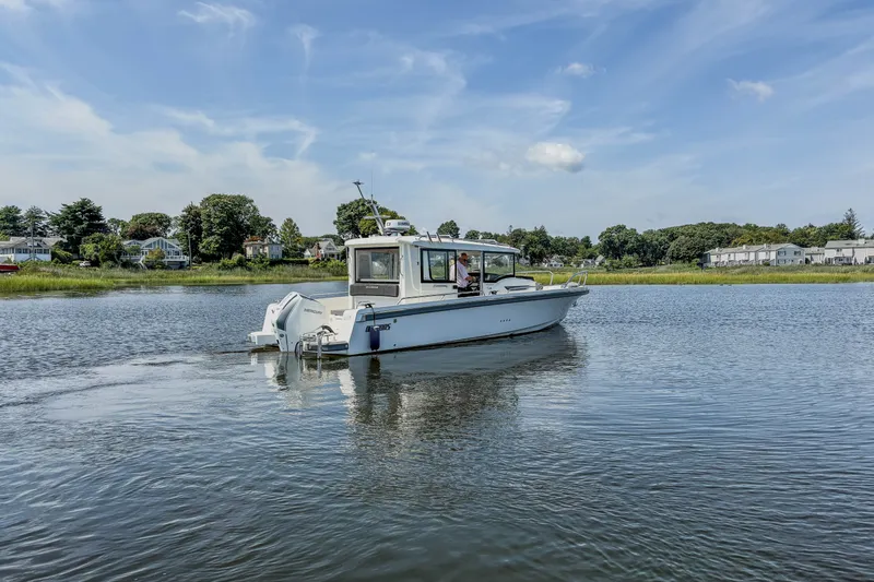Slide: The Image of 2024 Nimbus Commuter 9 boat cruising on a calm lake under a clear blue sky. - 5