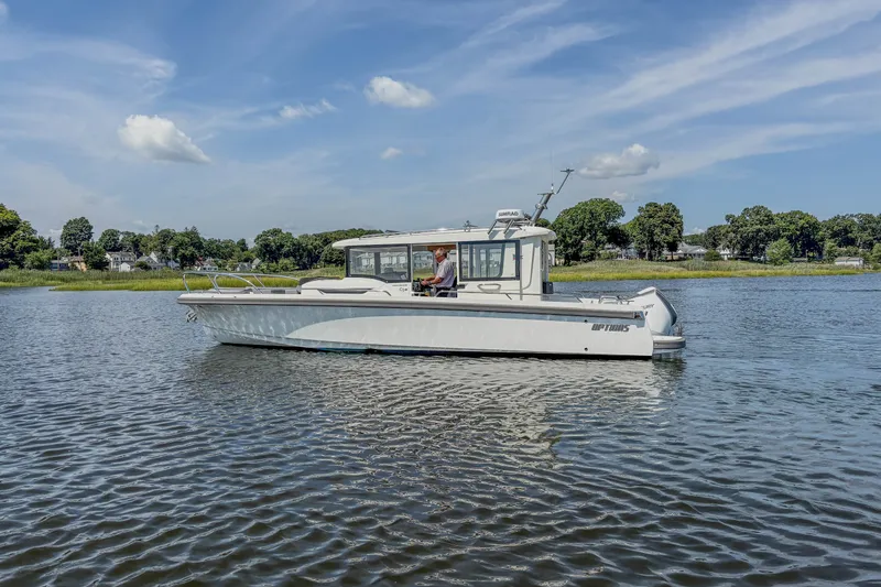 Slide: The Image of 2024 Nimbus Commuter 9 boat cruising on a calm lake under a clear blue sky. - 1