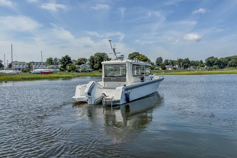 Slide: The Image of 2024 Nimbus Commuter 9 boat on calm water with scenic shoreline background. - 7