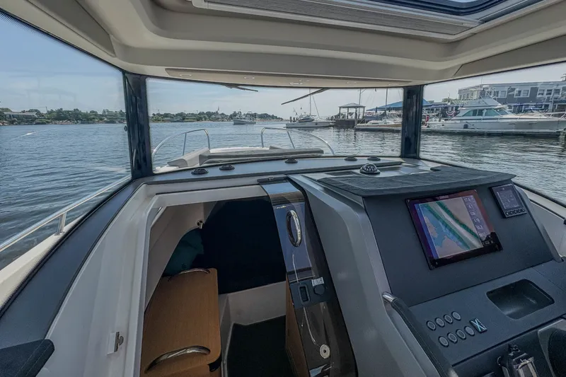 Slide: The Image of Interior view of 2024 Nimbus Commuter 9 boat with navigation system and waterfront scenery. - 12
