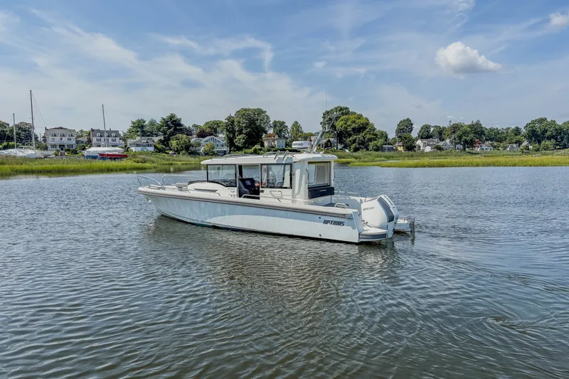 Slide: The Image of 2024 Nimbus Commuter 9 boat on calm water with scenic shoreline background. - 3