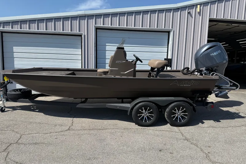 The Image of 2027 Avid 20 Rogue CC boat on trailer, parked outside a garage. - 1