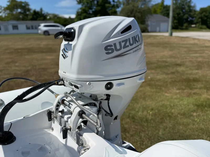 Slide: The Image of A Suzuki outboard motor is mounted on a Novurania 335DL boat, situated on a grassy area. - 20