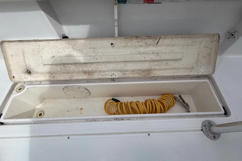 Slide: The Image of Open storage compartment on 2000 Cobia 274 Center Console boat with coiled yellow hose. - 7