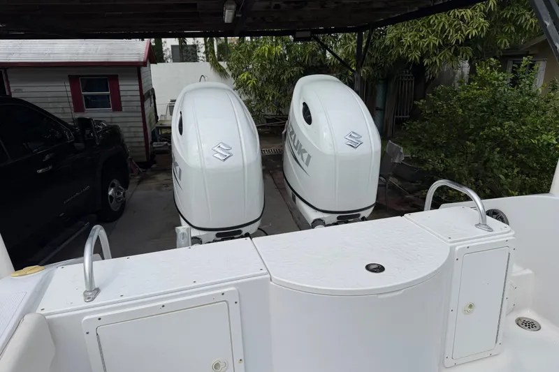 Slide: The Image of 2000 Cobia 274 Center Console with dual Suzuki outboard motors in a driveway setting. - 2