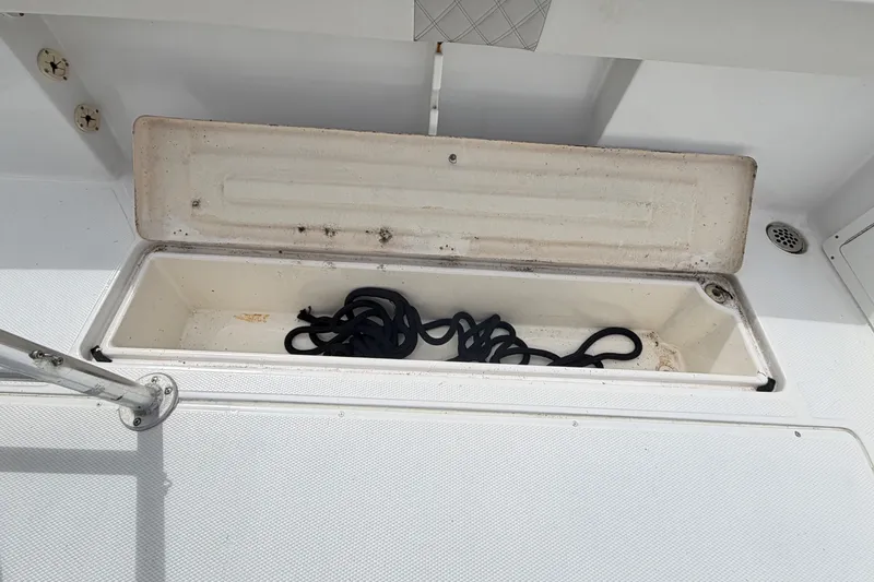 Slide: The Image of Open storage compartment on 2000 Cobia 274 Center Console boat with coiled rope inside. - 13