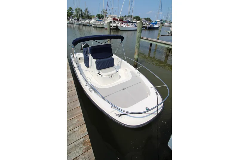 Slide: The Image of 2016 Boston Whaler 210 Dauntless boat docked at marina, featuring sleek design and bimini top. - 3