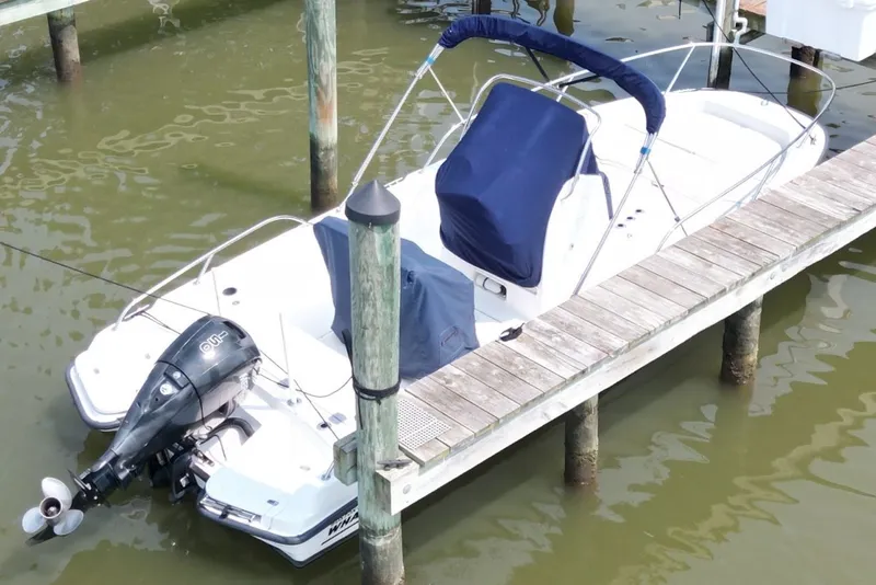 Slide: The Image of 2016 Boston Whaler 210 Dauntless boat docked with blue covers and outboard motor. - 7