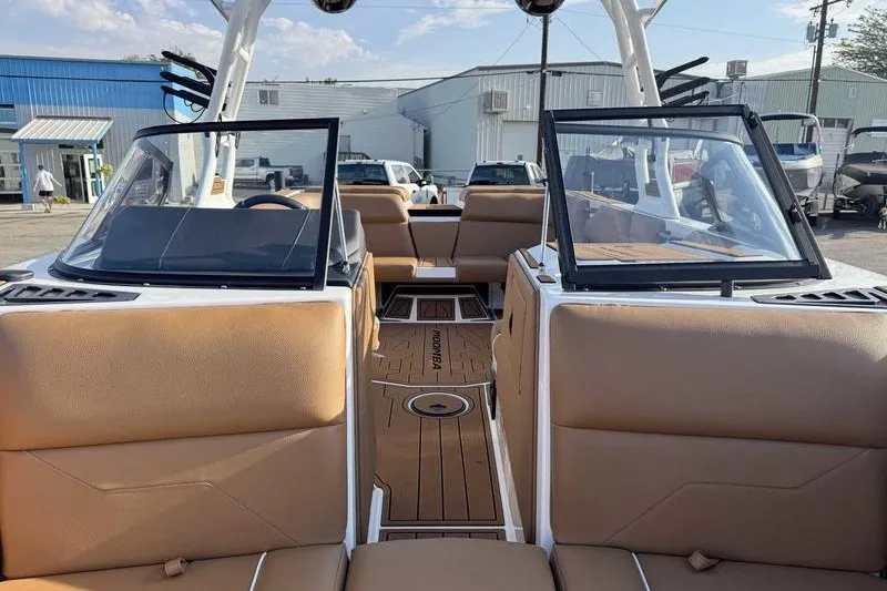 Slide: The Image of 2027 Moomba Max boat interior with tan seating and open windshield, parked outdoors. - 3