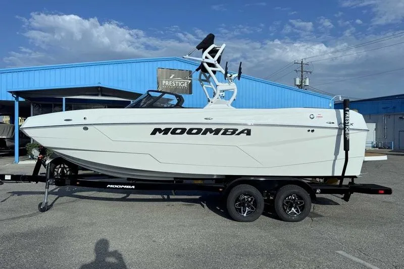 Slide: The Image of 2027 Moomba Max boat on trailer, parked outside a blue building under a clear sky. - 15