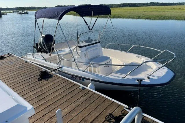 The Image of 2014 Boston Whaler 180 Dauntless boat docked on calm water with canopy. - 1