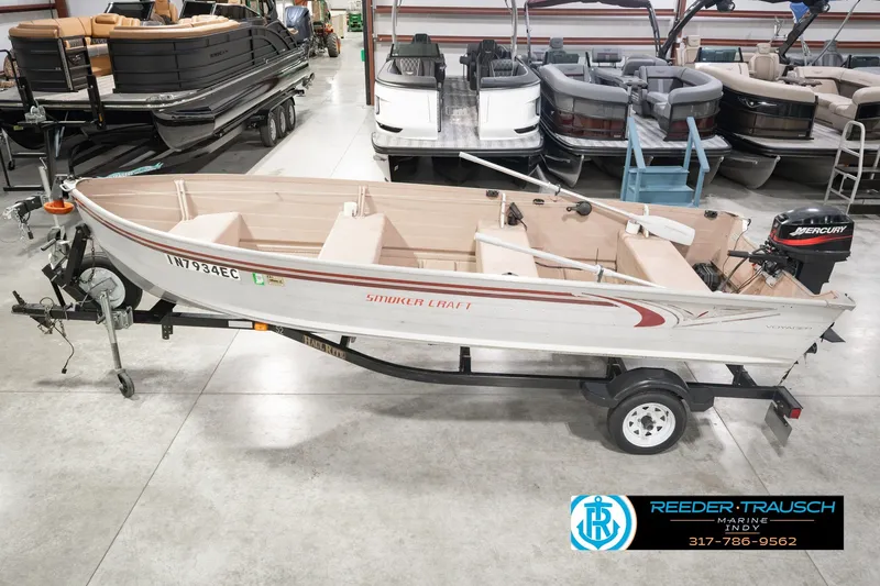 Slide: The Image of 2004 Smoker Craft Voyager boat on trailer in showroom with Mercury outboard motor. - 0