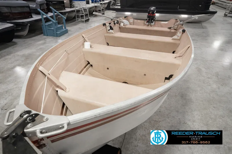 Slide: The Image of 2004 Smoker Craft Voyager boat in showroom, featuring beige interior and motor. - 12