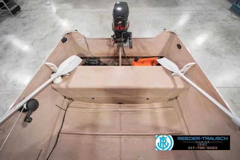 Slide: The Image of 2004 Smoker Craft Voyager boat interior with motor and oars in a showroom. - 24