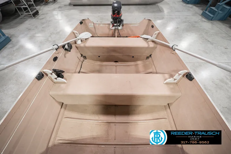 Slide: The Image of 2004 Smoker Craft Voyager boat interior with oars and motor, displayed in showroom. - 22