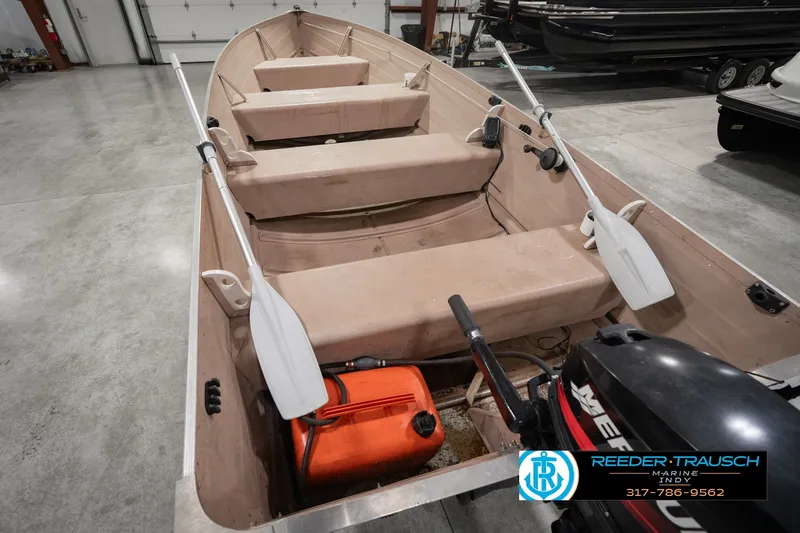 Slide: The Image of 2004 Smoker Craft Voyager boat with oars and motor in a showroom. - 16