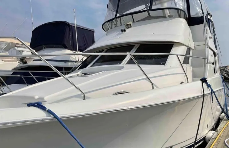 Slide: The Image of A 1997 Silverton 372 Motor Yacht docked in a marina. It features a sleek, white design. - 25