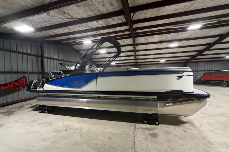 The Image of 2027 Harris Sunliner 230 pontoon boat in a spacious indoor storage facility. - 0