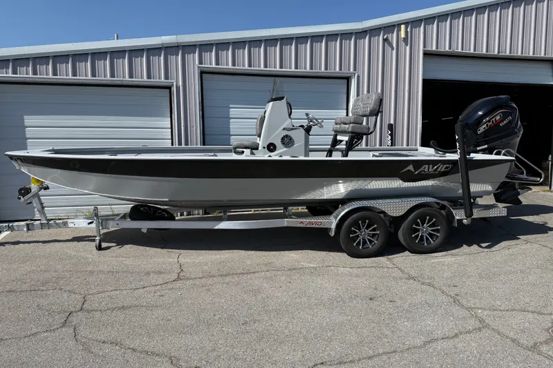 The Image of 2027 Avid 23 Mag boat on trailer, parked outside metal garage. - 1