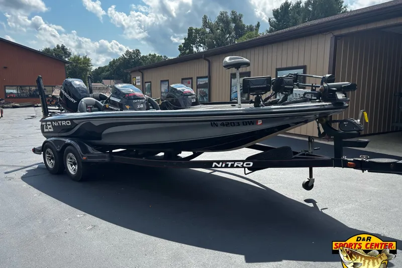 Slide: The Image of 2012 Nitro Z-8 fishing boat on trailer, parked outside a sports center. - 1