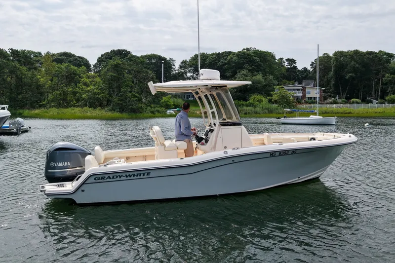 Slide: The Image of 2022 Grady-White Fisherman 216 boat on calm water, with Yamaha engine, near lush shoreline. - 7