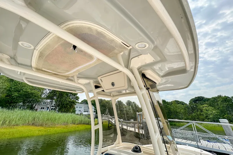 Slide: The Image of 2022 Grady-White Fisherman 216 boat canopy and console, docked near lush greenery. - 15