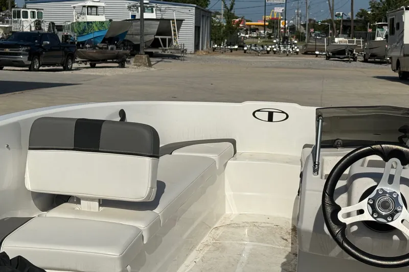 Slide: The Image of 2025 Tahoe T16 boat interior with steering wheel and seating, parked outdoors. - 14