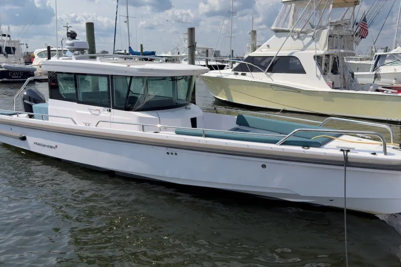 The Image of A 2023 Axopar 28 Cabin boat is in the water, surrounded by other boats in the harbor. - 1