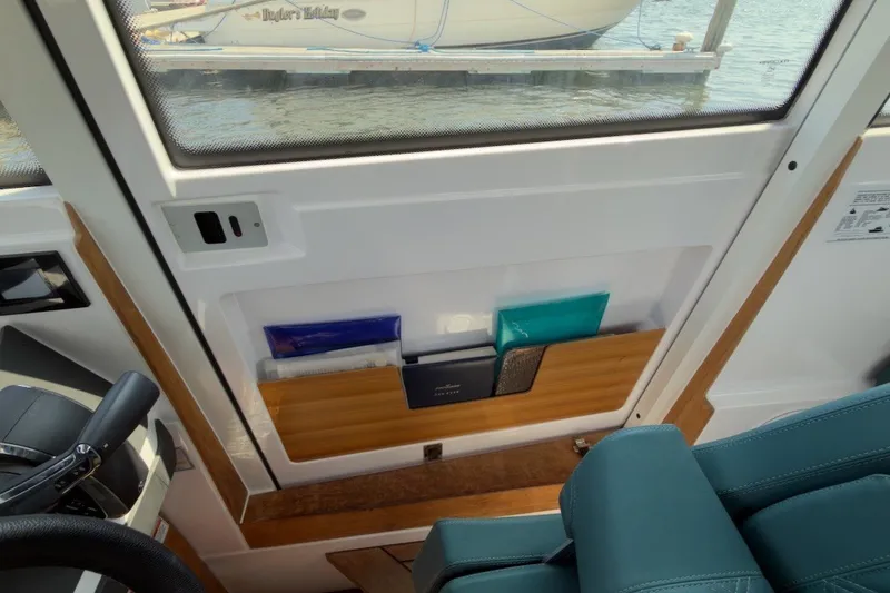 Slide: The Image of 2023 Axopar 28 Cabin interior with storage compartment and teal seating. - 31