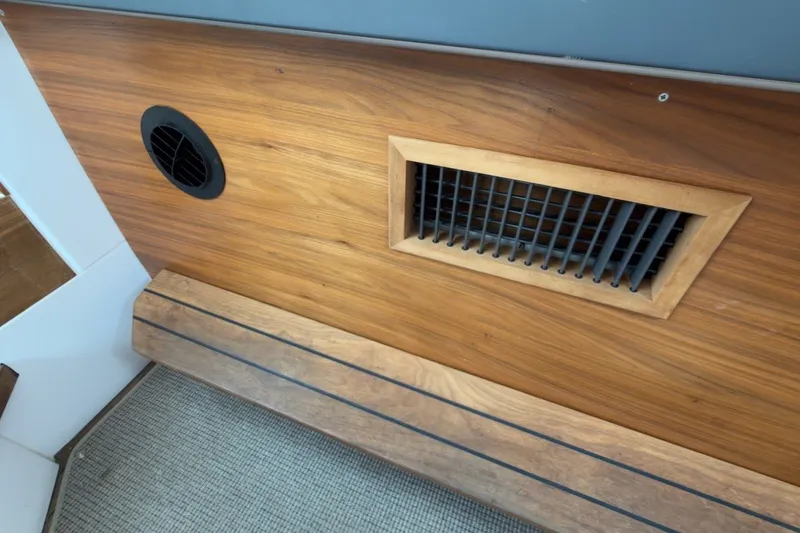 Slide: The Image of Interior detail of 2023 Axopar 28 Cabin, featuring wooden paneling and ventilation grille. - 33