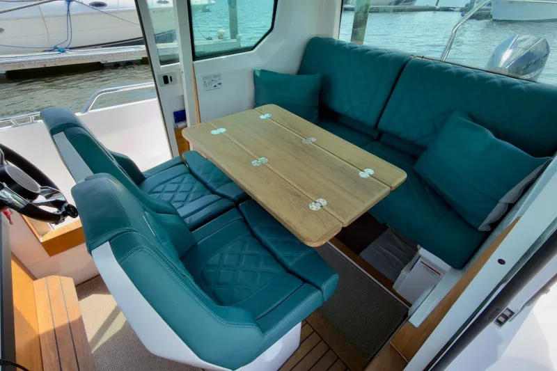Slide: The Image of Interior of 2023 Axopar 28 Cabin with teal seating and wooden table. - 17