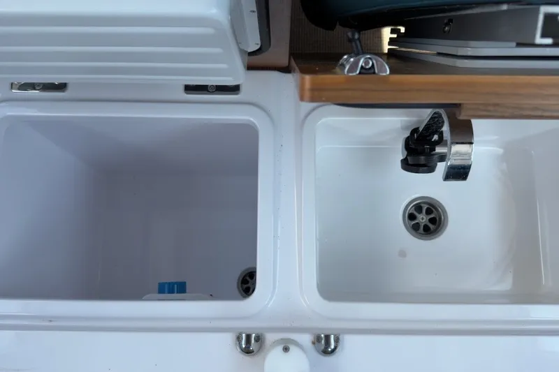 Slide: The Image of The 2023 Axopar 28 Cabin features a modern sink and storage area in the galley. - 19