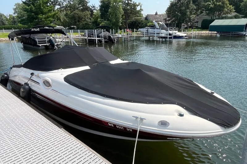 The Image of 2007 Sea Ray 240 Sundeck boat docked with black cover on a sunny day. - 0