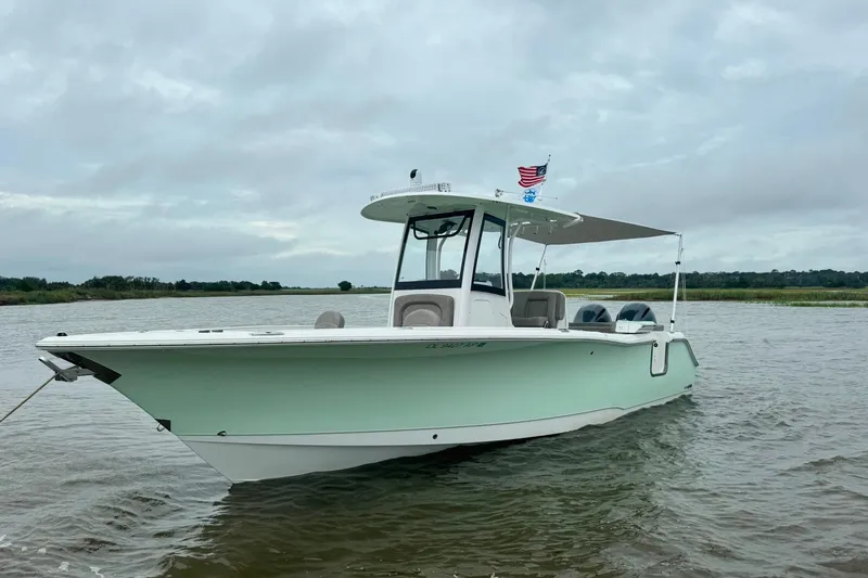 The Image of 2020 Sea Hunt Ultra 275SE boat on calm water with canopy and flags. - 1