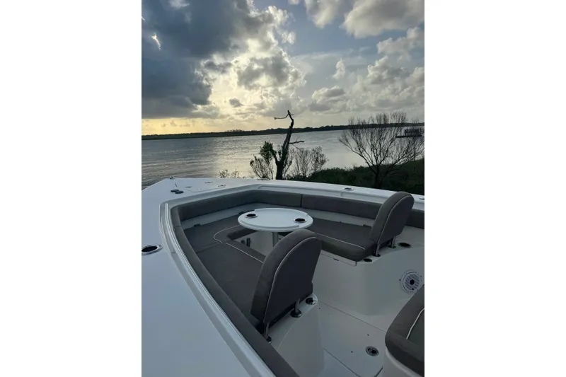 Slide: The Image of 2020 Sea Hunt Ultra 275SE boat interior with seating, overlooking a serene waterfront at sunset. - 18