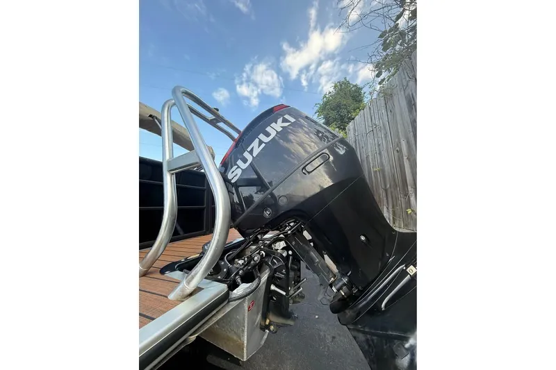 Slide: The Image of 2024 Bentley Pontoons Legacy 243 DL Navigator with Suzuki outboard motor, docked under blue sky. - 3