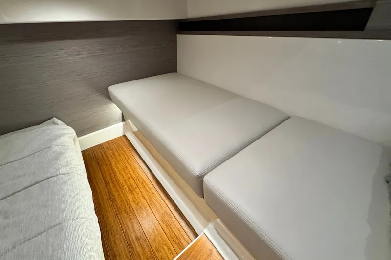 Slide: The Image of 2023 Tiara Yachts 43 LE interior cabin with sleek white seating and wooden flooring. - 52