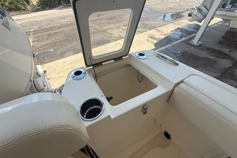 Slide: The Image of Open storage compartment on a 2027 Scout 240 XSF boat, featuring cup holders and seating. - 13