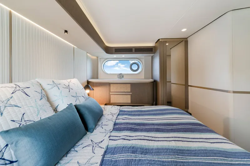Slide: The Image of Luxurious cabin of the 2024 Azimut Magellano with a large bed and a porthole. - 33
