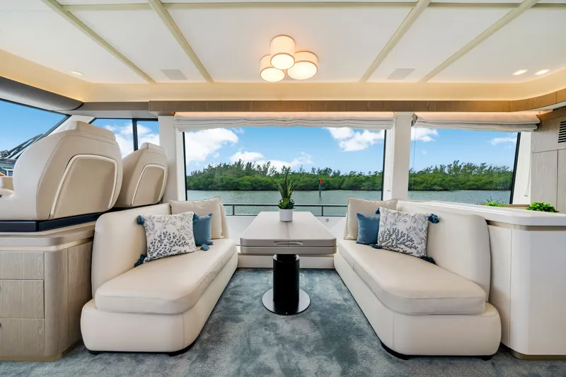 Slide: The Image of Interior of the 2024 Azimut Magellano with elegant sofas and large windows overlooking the water. - 24