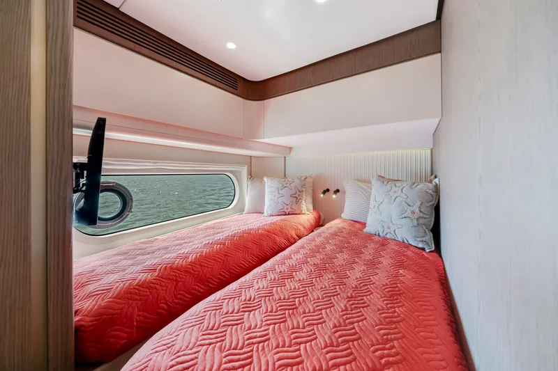 Slide: The Image of The Azimut Magellano 2024 cabin features twin beds with red covers and a porthole. - 39