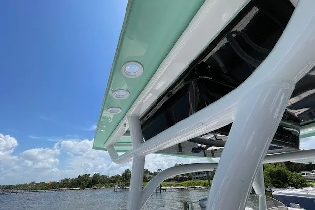 Slide: The Image of 2023 Wellcraft 242 Fisherman boat canopy with rod holders, set against a scenic waterfront. - 36
