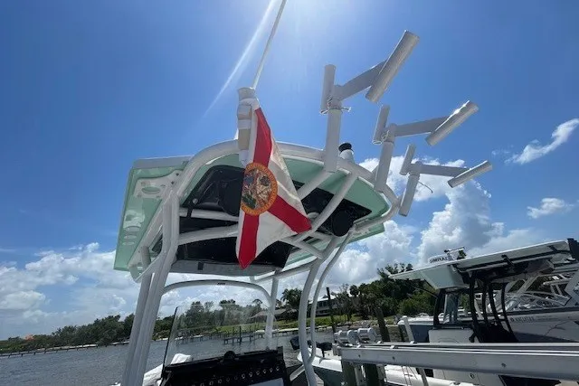 Slide: The Image of 2023 Wellcraft 242 Fisherman boat with Florida flag, clear sky, and fishing rod holders. - 31