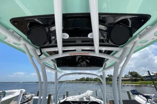Slide: The Image of 2023 Wellcraft 242 Fisherman boat with sleek overhead console and speakers, docked by the water. - 29